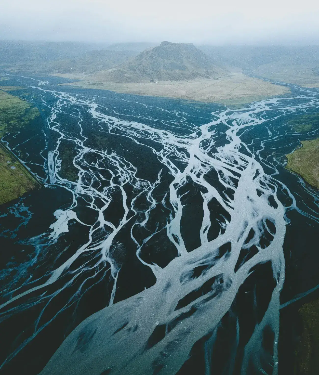 Aerial view of a braided glacial river splitting into many channels across a valley floor