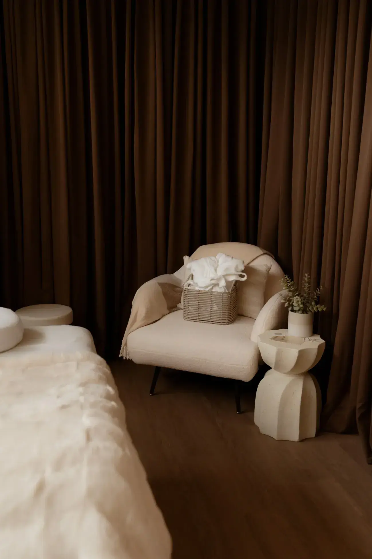 An armchair and folded towels in the dim BodyTox room