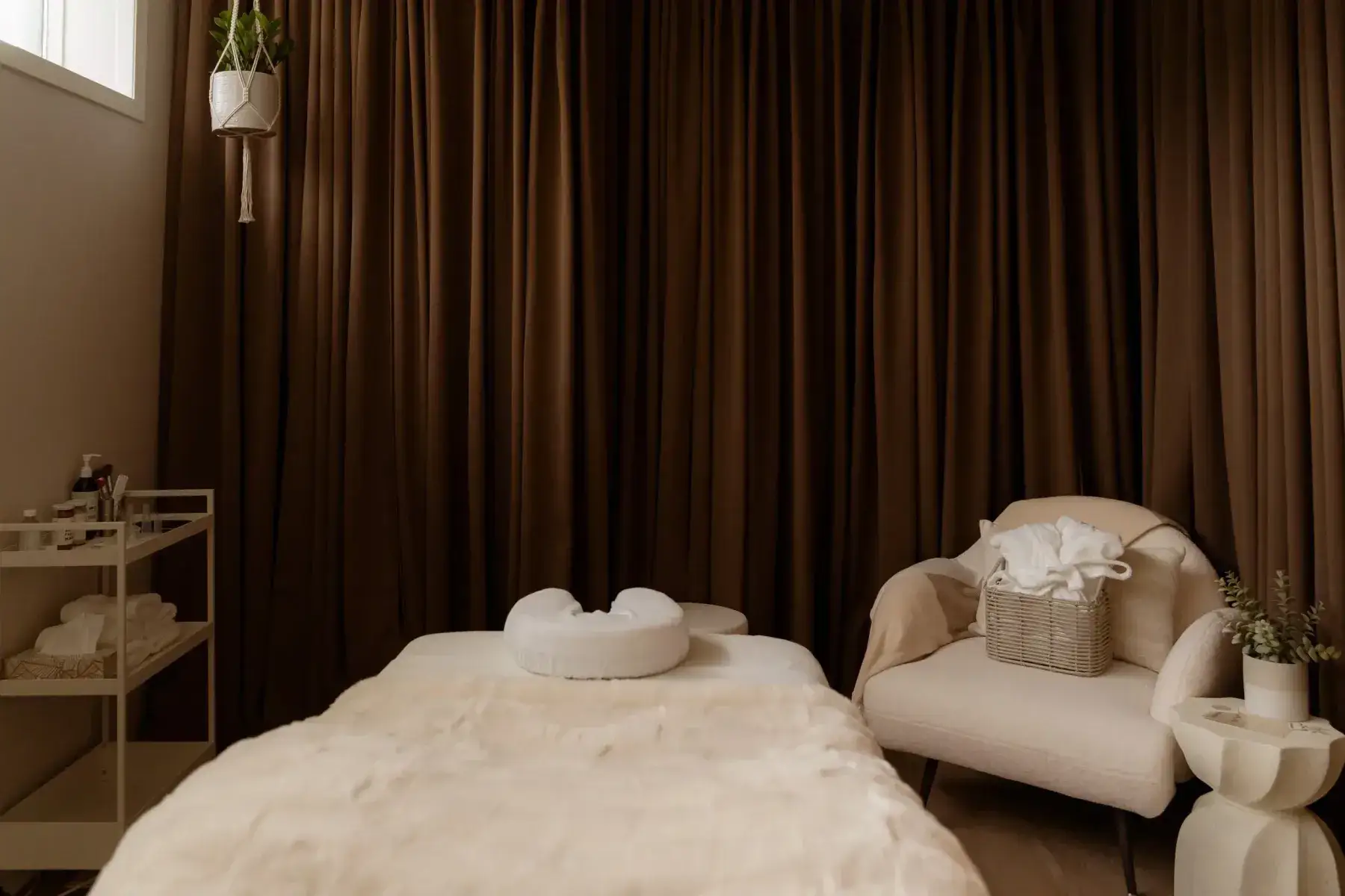The BodyTox by Renu treatment room, with its bed, umber curtains and a lounge chair