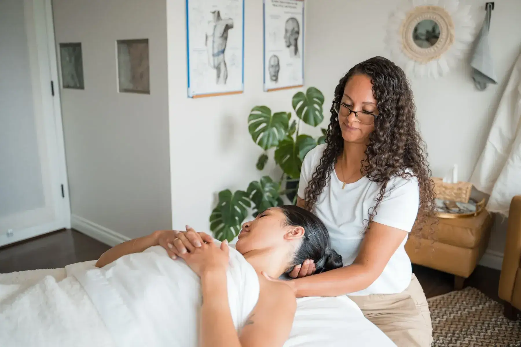Sasha Bernard treating a client’s neck and shoulders in a bright treatment room at Renu