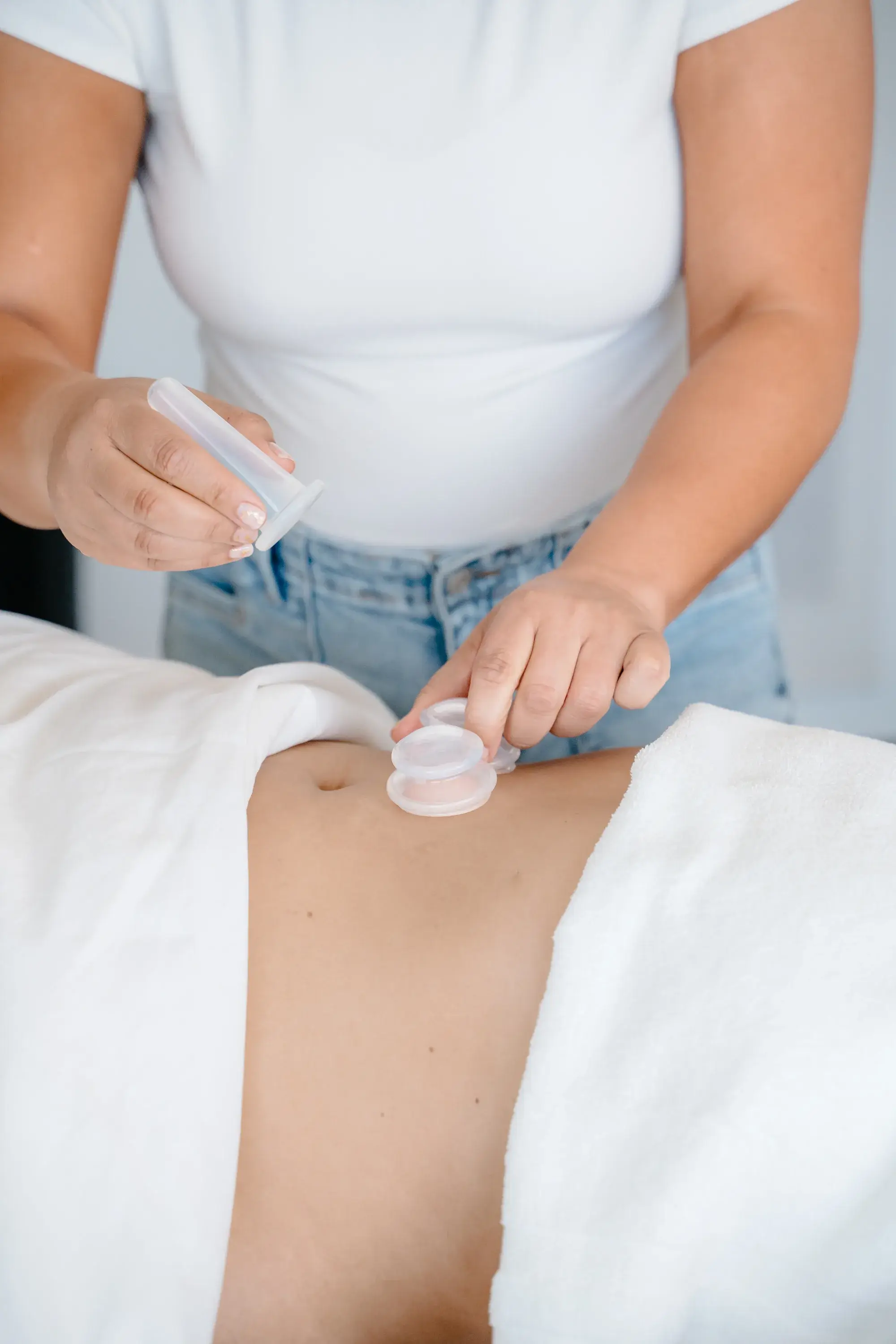 A therapist's hands resting lightly on a client's abdomen during a lymphatic session