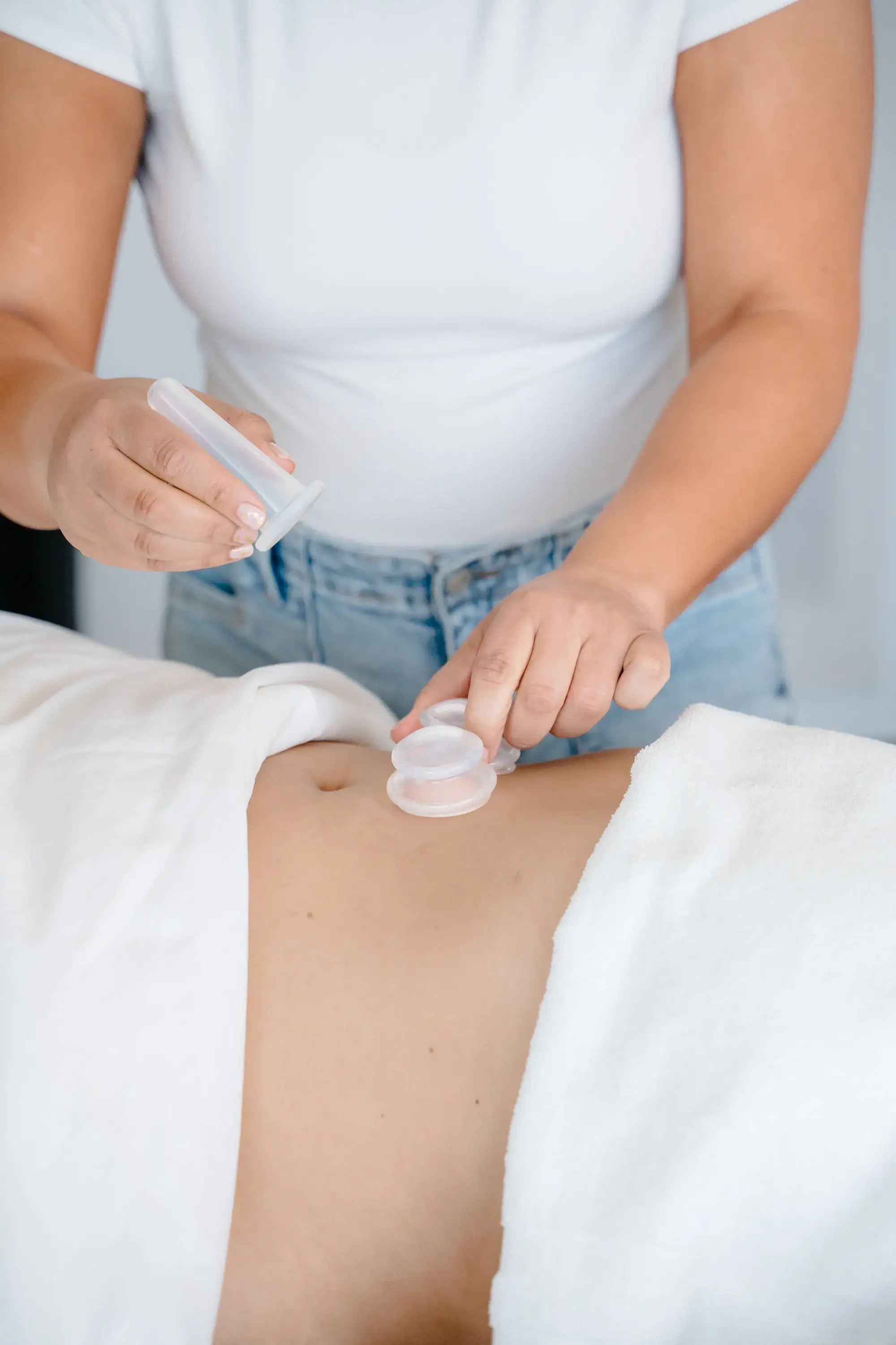 Flat hands resting lightly on the abdomen during post-operative lymphatic drainage at Renu