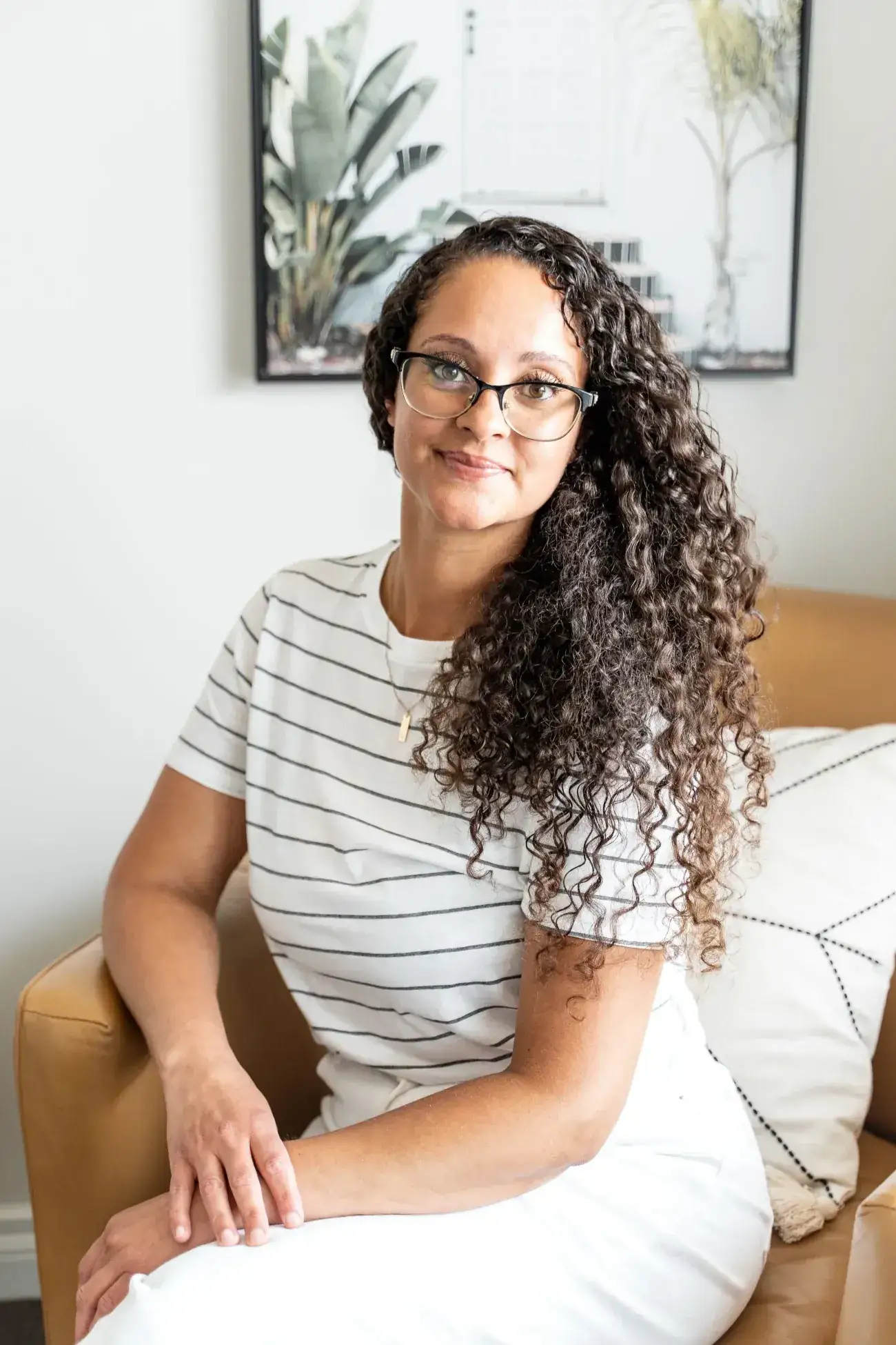 Sasha Bernard, the Registered Massage Therapist who delivers prenatal and postnatal massage at Renu, seated in a leather armchair in the clinic lounge