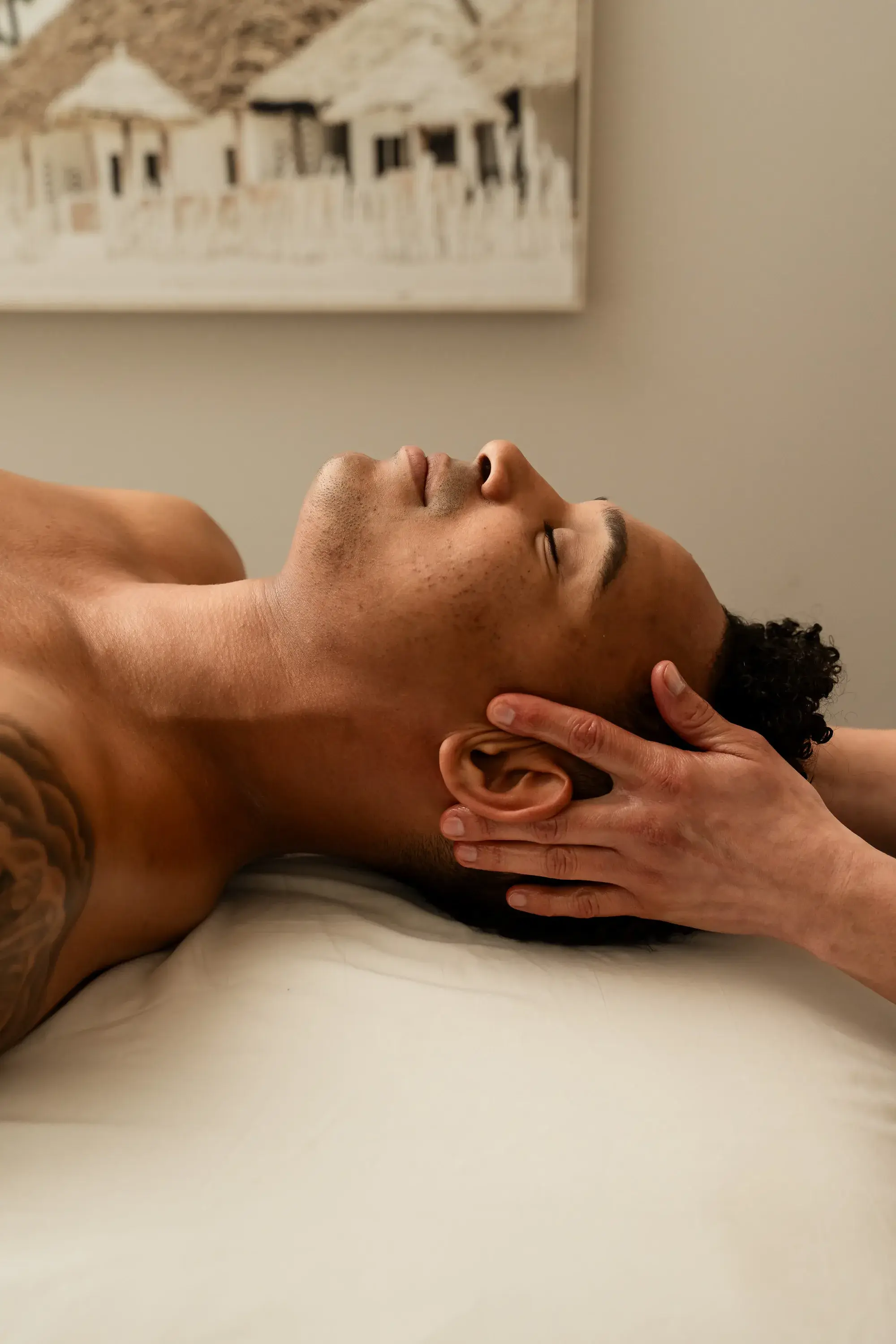 A Renu therapist applying broad strokes across the back of a client lying face down on the treatment table