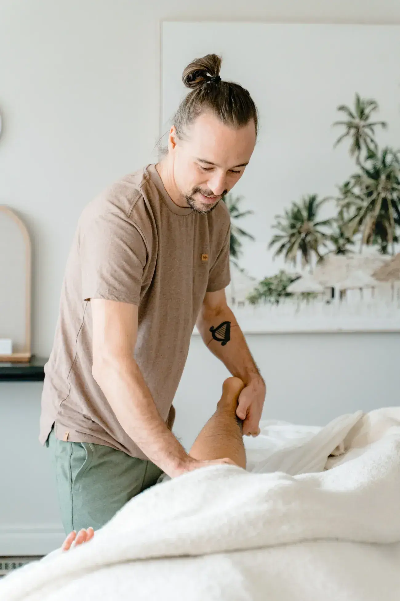Dr. Will Tanner working along a client's lower leg on a draped treatment table at Renu
